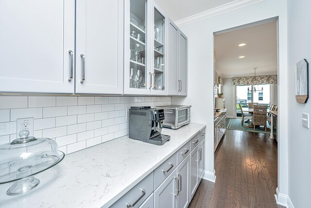 2234 Mother Of Pearl Dr, Mount Pleasant, SC 29466 - kitchen with light stone counters, glass insert cabinets, dark wood finished floors, tasteful backsplash, and crown molding