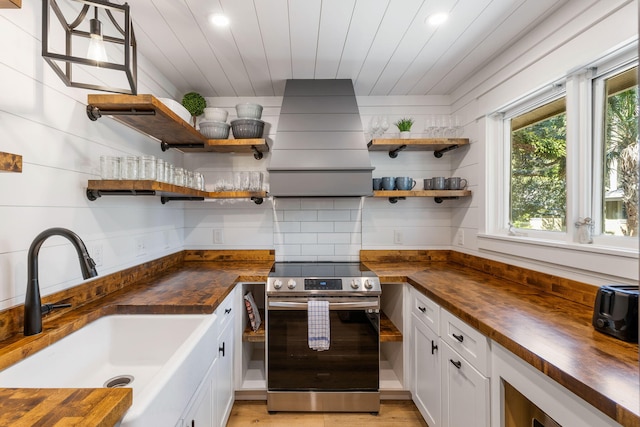 kitchen with stainless steel electric range oven, open shelves, wooden counters, and a sink