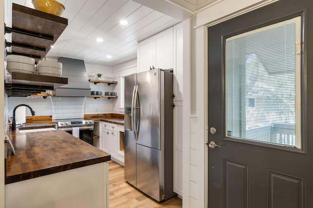 kitchen with light wood finished floors, open shelves, a sink, appliances with stainless steel finishes, and wood counters