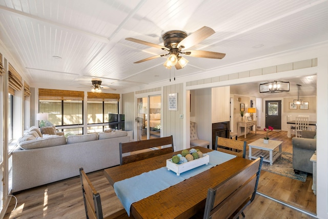 dining space featuring wood ceiling, wood finished floors, crown molding, and ceiling fan with notable chandelier