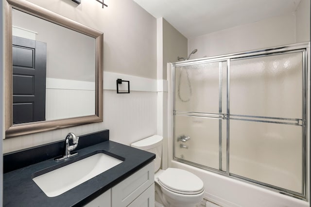 full bath featuring vanity, toilet, and shower / bath combination with glass door