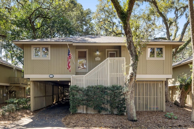 view of front of home with aphalt driveway, stairs, and a carport