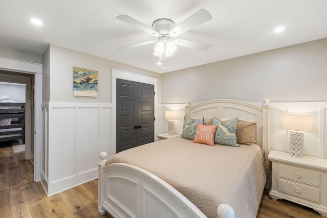bedroom with a wainscoted wall, recessed lighting, light wood-style flooring, a decorative wall, and a ceiling fan