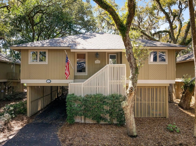 view of front of property with a carport, covered porch, driveway, and a shingled roof