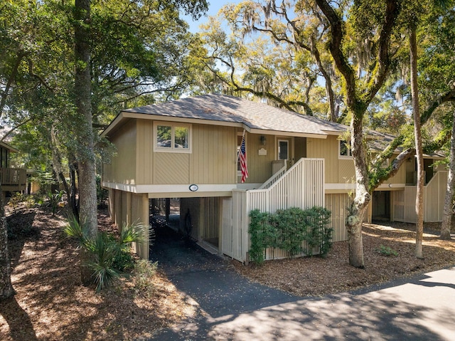 view of front facade with a carport, stairs, and aphalt driveway