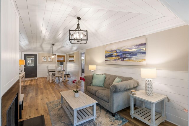 living room with hardwood / wood-style floors, lofted ceiling, a notable chandelier, and wood ceiling