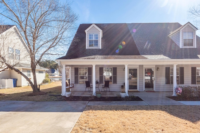 cape cod home featuring a porch and a front yard