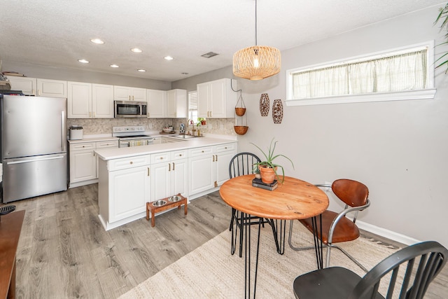 kitchen featuring appliances with stainless steel finishes, decorative light fixtures, white cabinetry, sink, and decorative backsplash