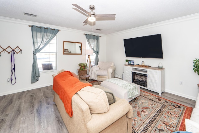 living room featuring crown molding, ceiling fan, wood-type flooring, and a textured ceiling