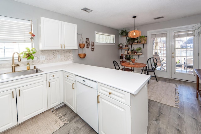 kitchen with decorative light fixtures, white cabinetry, dishwasher, sink, and kitchen peninsula