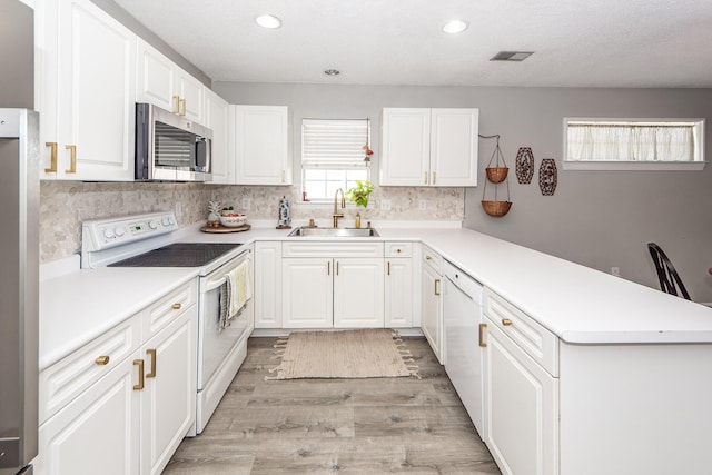 kitchen featuring sink, white cabinetry, light wood-type flooring, white appliances, and decorative backsplash