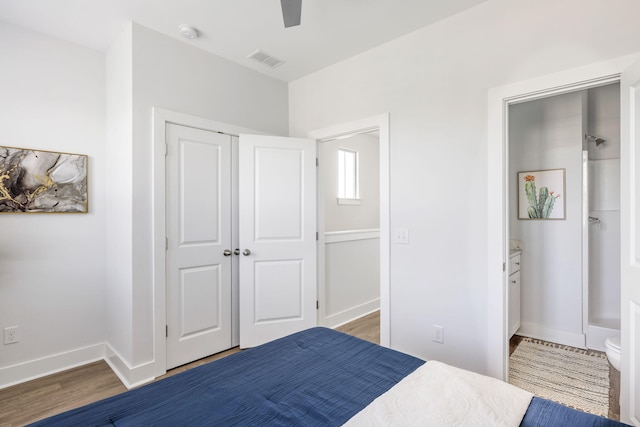 bedroom featuring wood finished floors, visible vents, baseboards, a closet, and ensuite bath