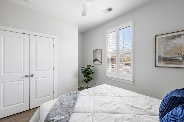 bedroom with ceiling fan, a closet, wood finished floors, and visible vents