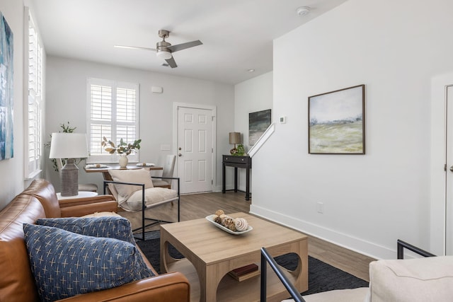 living room featuring a ceiling fan, baseboards, and wood finished floors