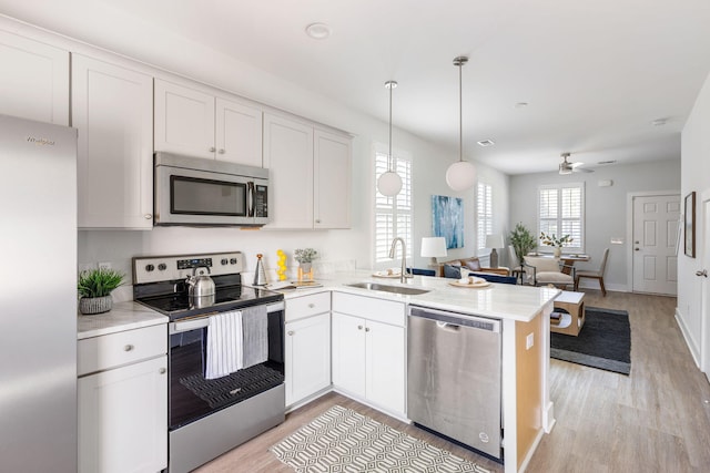 kitchen featuring open floor plan, stainless steel appliances, a sink, and light countertops