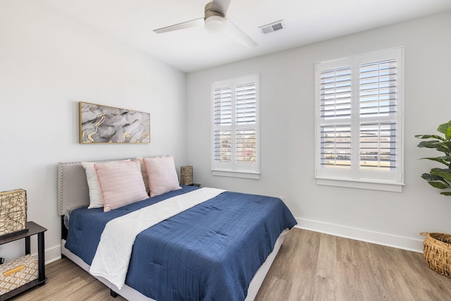 bedroom featuring ceiling fan, wood finished floors, visible vents, and baseboards