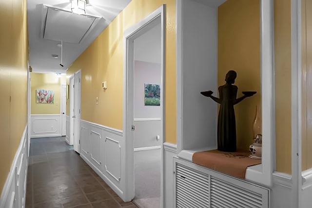 hallway featuring a wainscoted wall, attic access, and a decorative wall