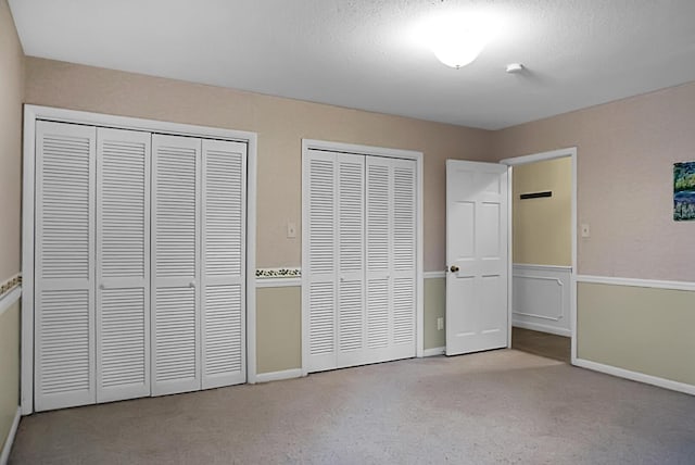 unfurnished bedroom with carpet floors, baseboards, and two closets