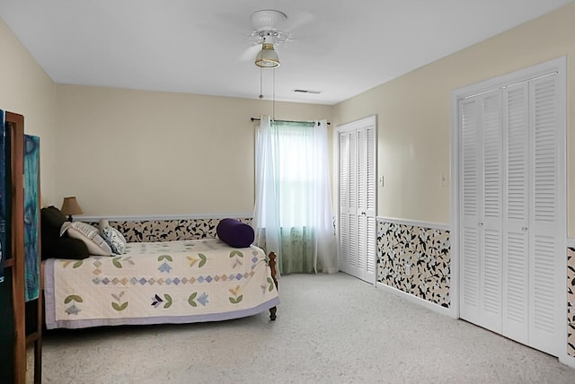carpeted bedroom featuring ceiling fan and two closets