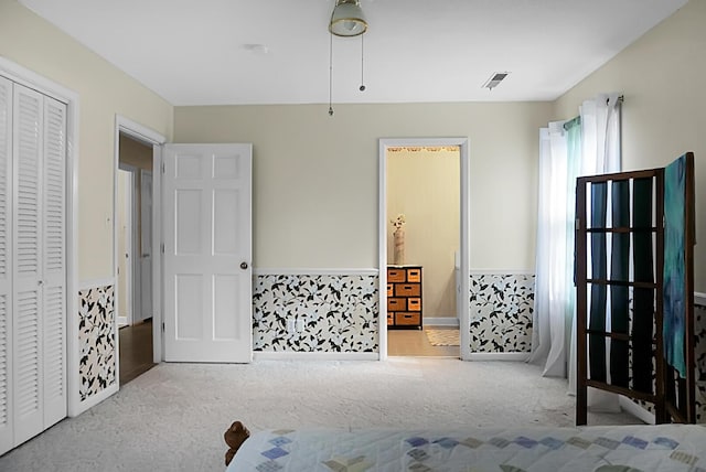 bedroom with visible vents, ensuite bathroom, carpet, and a closet