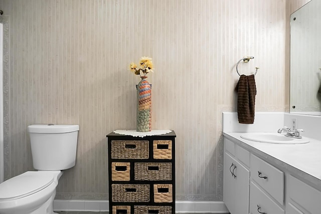 bathroom featuring vanity, baseboards, tile patterned floors, and toilet