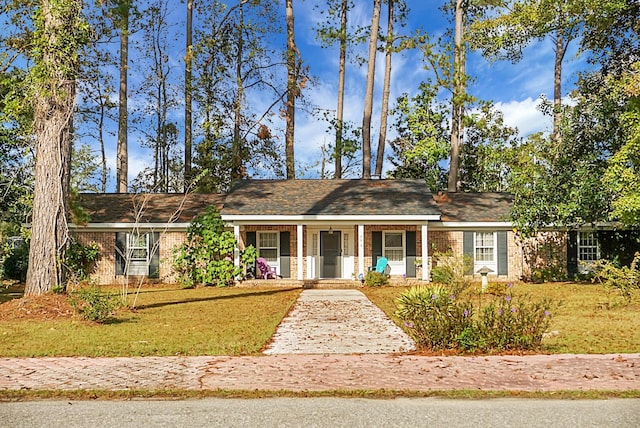 single story home featuring covered porch, brick siding, and a front lawn