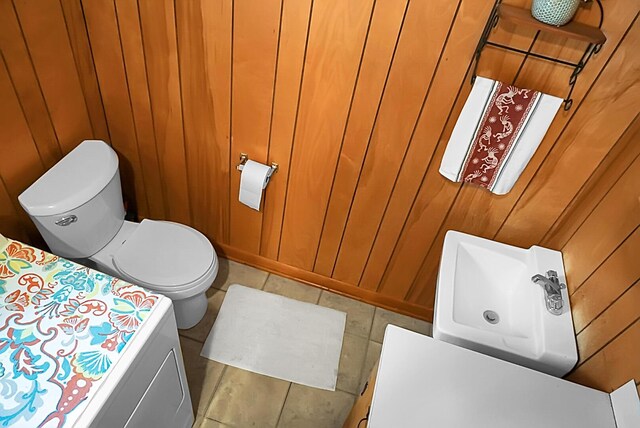 bathroom with toilet and wood walls