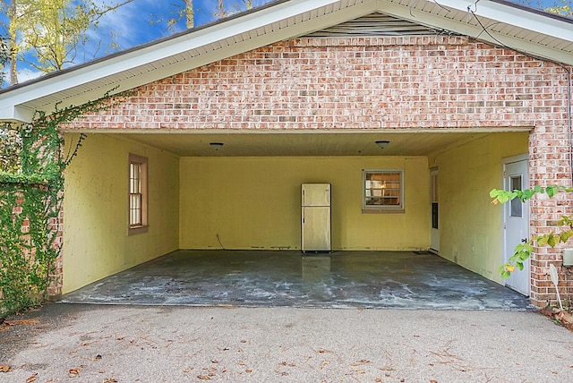 exterior space featuring brick siding, driveway, and an attached carport