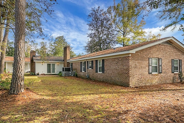 back of property featuring a lawn and brick siding