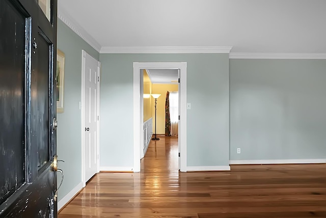 foyer featuring crown molding, baseboards, and wood finished floors