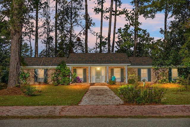 ranch-style home with a lawn, a porch, and brick siding