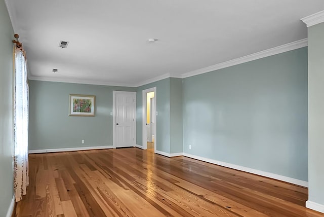 unfurnished room featuring baseboards, crown molding, and wood finished floors
