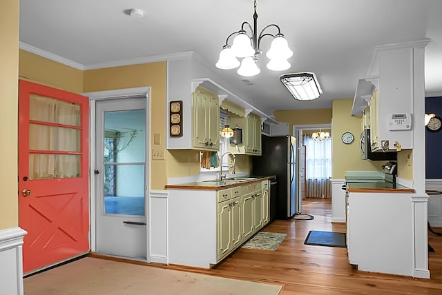 kitchen with ornamental molding, light wood-type flooring, a chandelier, a sink, and stainless steel appliances