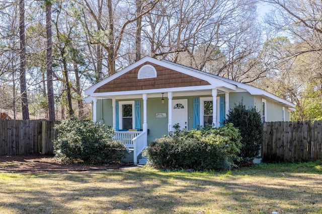 bungalow with a porch, a front lawn, and fence