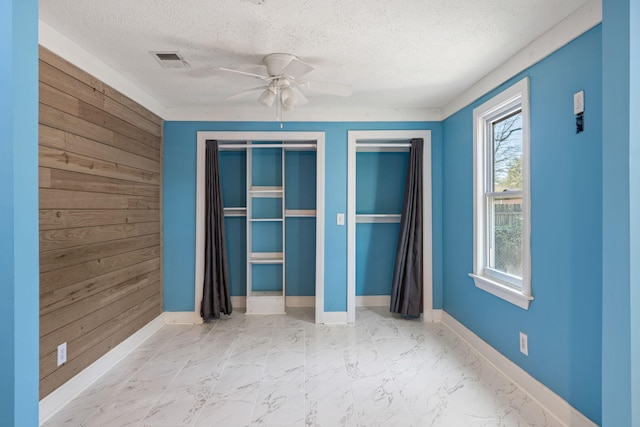 unfurnished bedroom with visible vents, baseboards, marble finish floor, and a textured ceiling