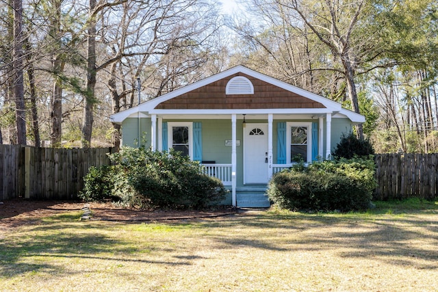 bungalow-style home with a porch, a front lawn, and fence