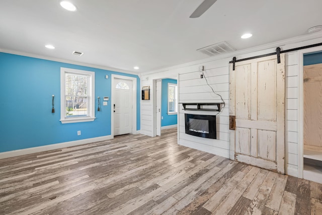 unfurnished living room featuring visible vents, wood finished floors, and ornamental molding