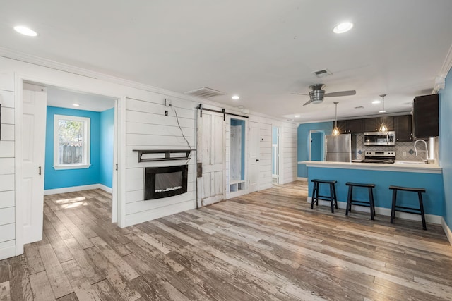 kitchen featuring visible vents, backsplash, a barn door, wood finished floors, and stainless steel appliances