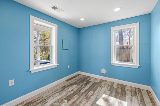 unfurnished room featuring wood finished floors, recessed lighting, baseboards, and visible vents