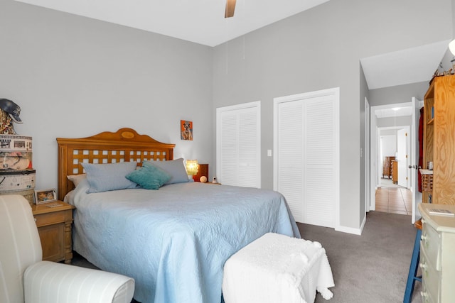 carpeted bedroom featuring ceiling fan, two closets, and attic access