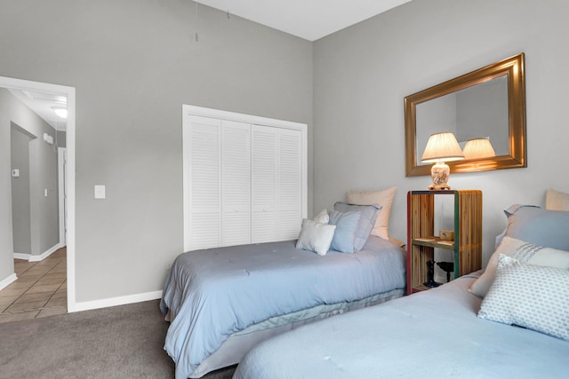 tiled bedroom featuring a closet, carpet flooring, attic access, and baseboards