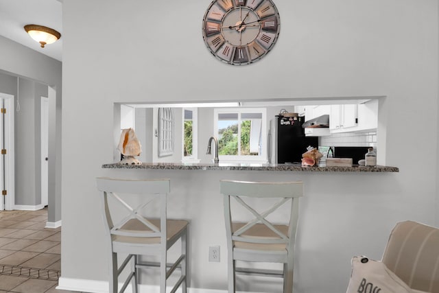 bar with light tile patterned floors, extractor fan, a sink, and freestanding refrigerator