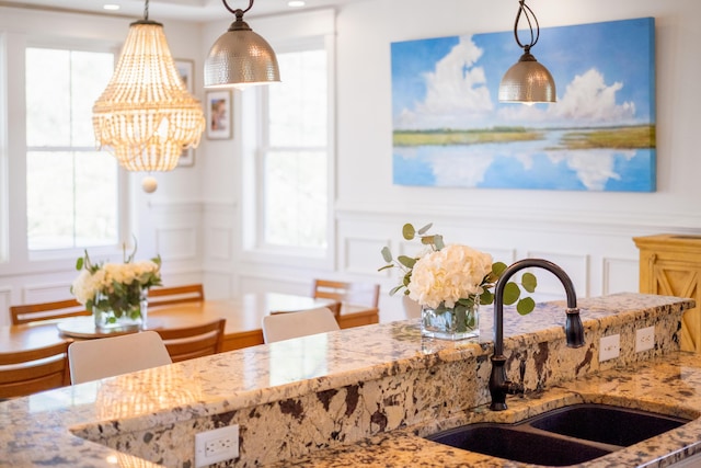 1543 Wando Landing St, Charleston, SC 29492 - kitchen with a decorative wall, a sink, light stone counters, a chandelier, and pendant lighting