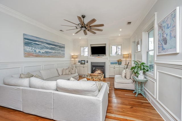 1543 Wando Landing St, Charleston, SC 29492 - living room featuring a decorative wall, ornamental molding, ceiling fan, light wood finished floors, and a glass covered fireplace