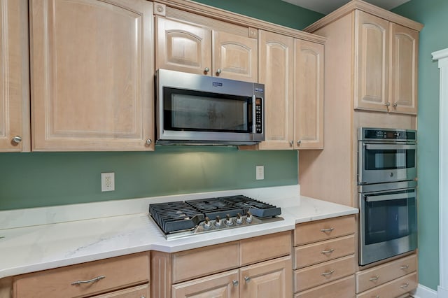 kitchen with appliances with stainless steel finishes, light brown cabinets, and light stone countertops