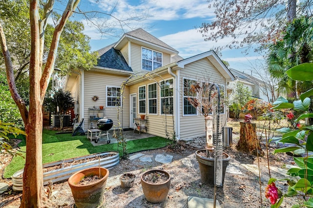 back of property featuring a shingled roof, a lawn, and a patio area