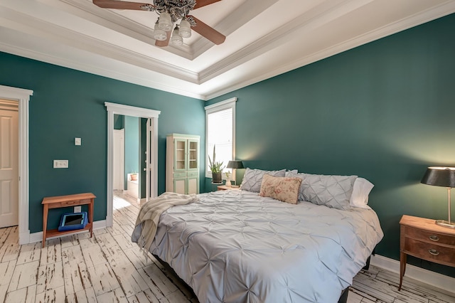 bedroom featuring ornamental molding, a tray ceiling, baseboards, and wood finished floors