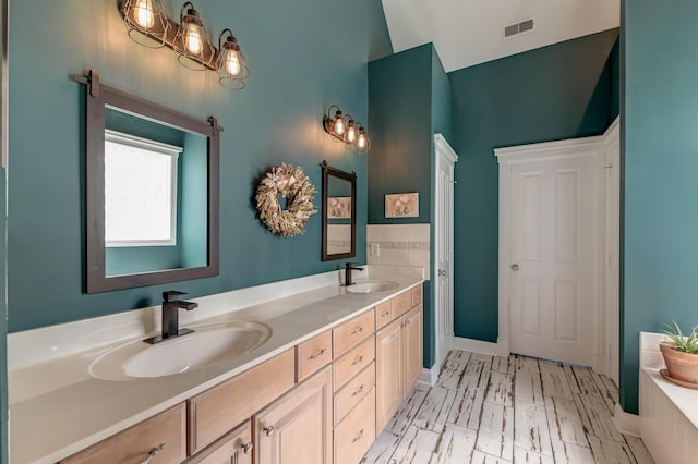 bathroom featuring double vanity, a tub to relax in, a sink, and visible vents