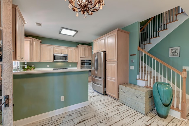 kitchen with light brown cabinetry, a peninsula, appliances with stainless steel finishes, and visible vents