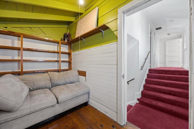 interior space with visible vents, vaulted ceiling with beams, stairway, wood walls, and wood finished floors